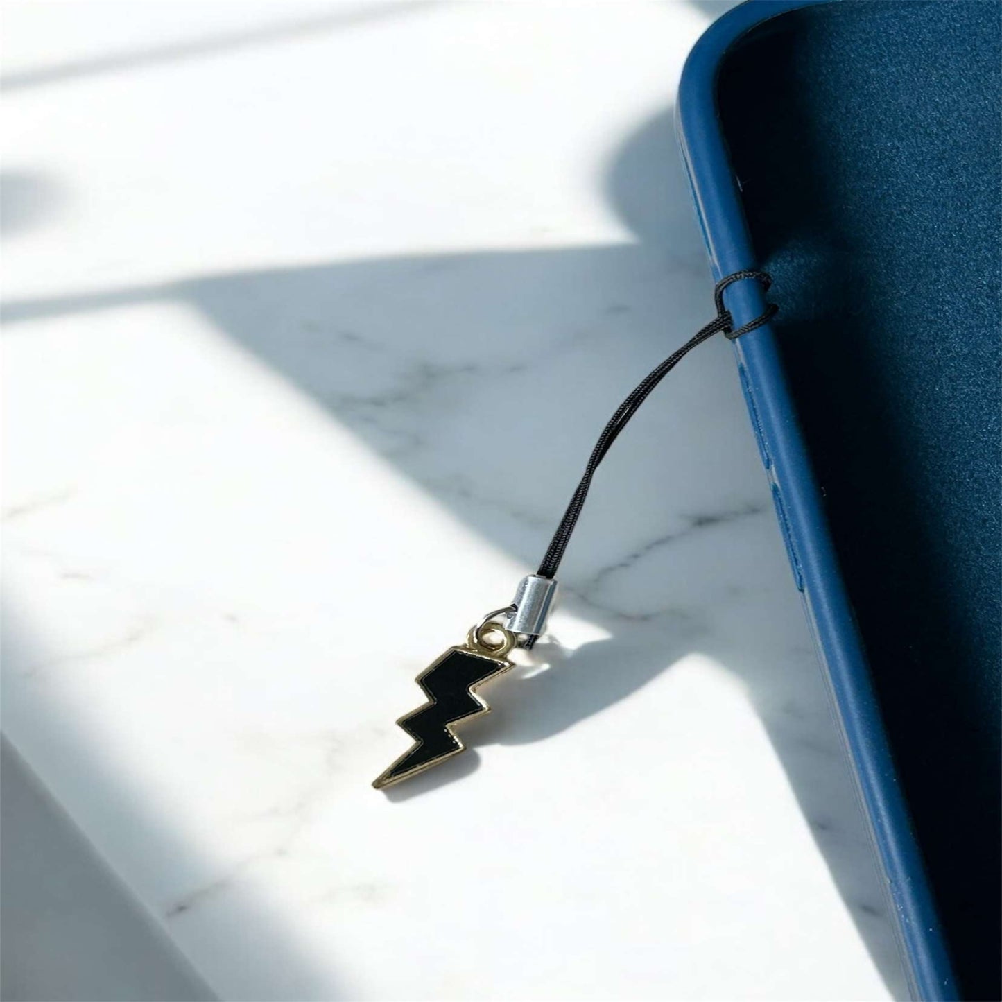 Phone charm with lightning bolt design attached to a phone on a marble surface - Thecharmingcharms09