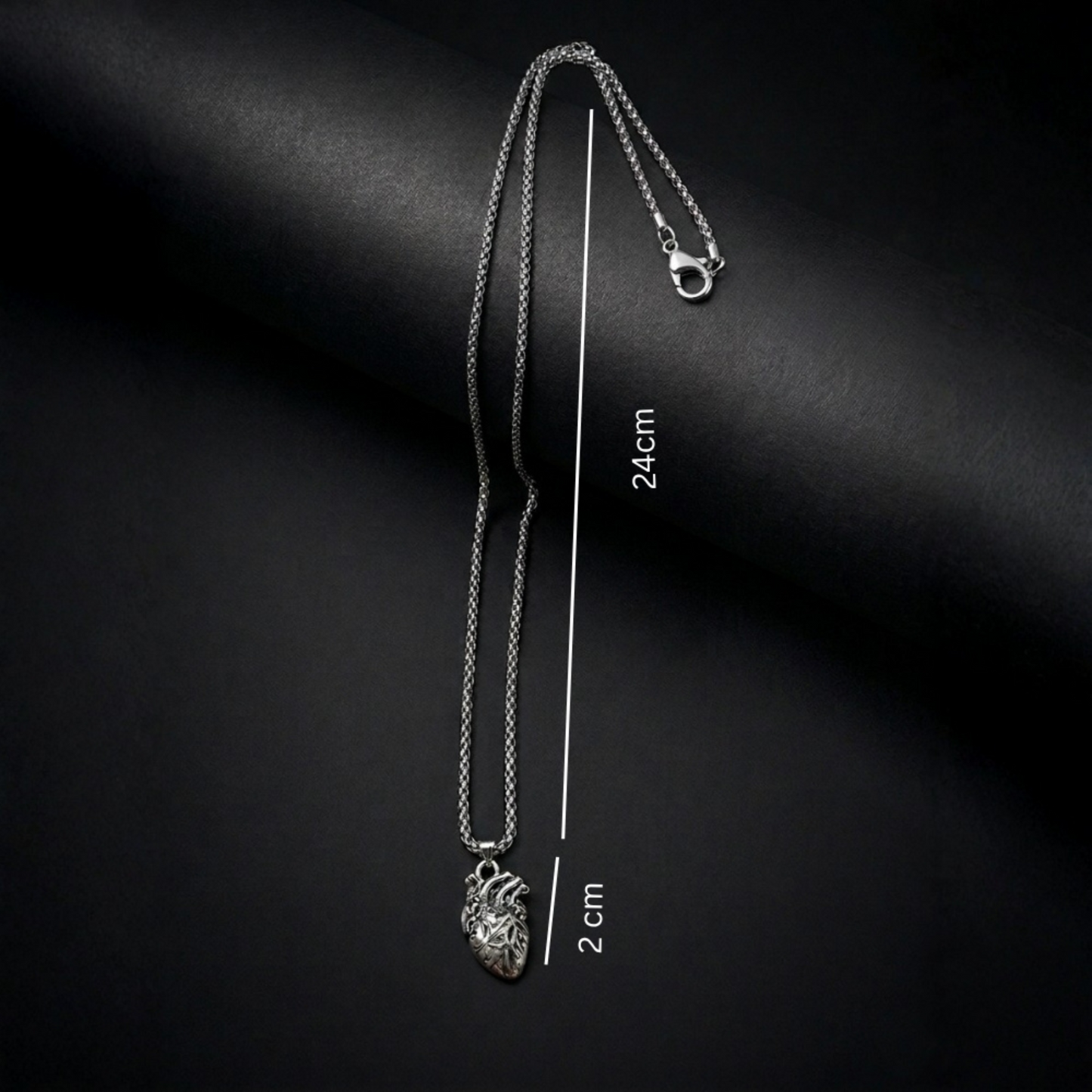 Silver necklace with a heart pendant on a black background, showing measurements.