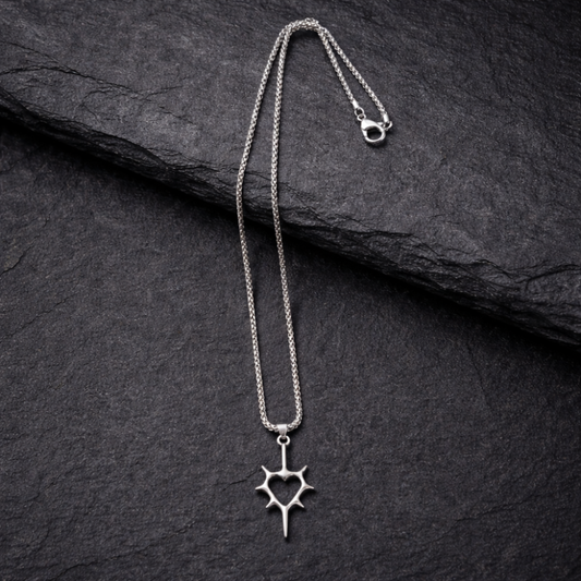 Silver necklace with a star-shaped pendant on a dark stone surface