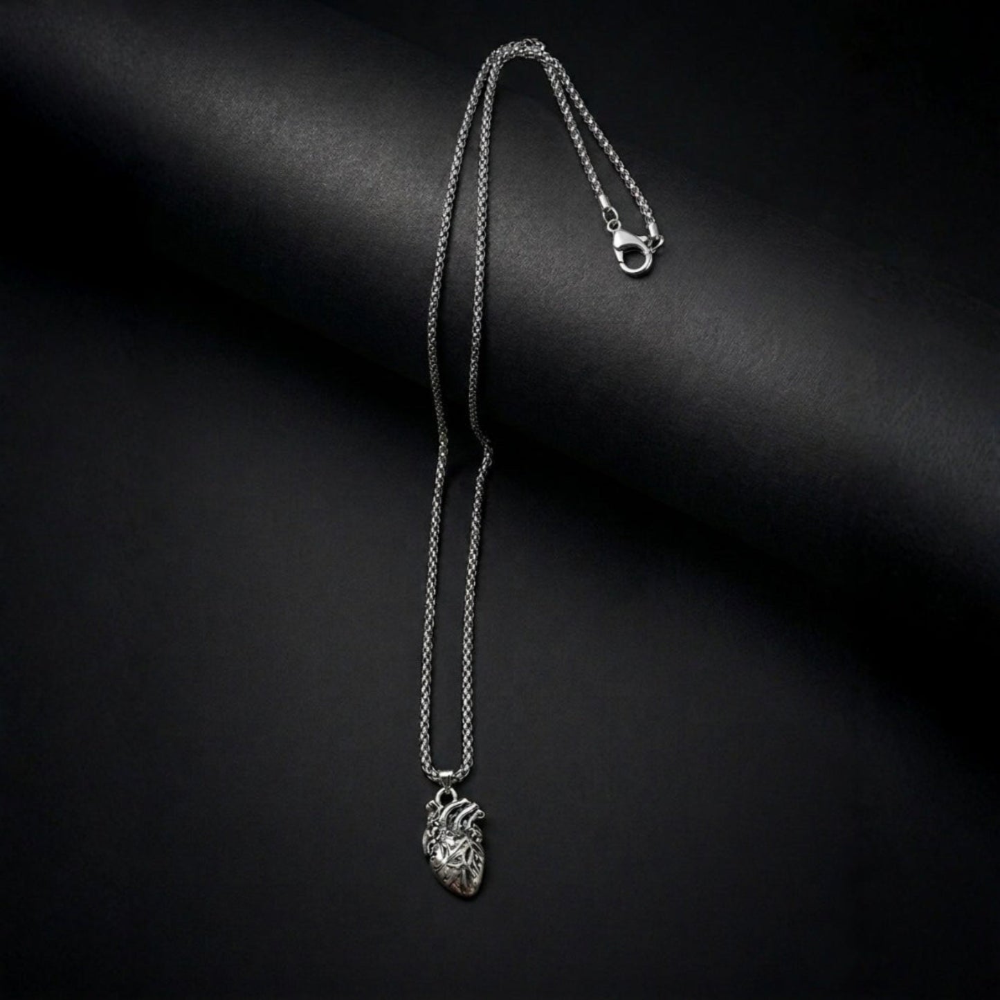 Silver necklace with a heart pendant on a black background