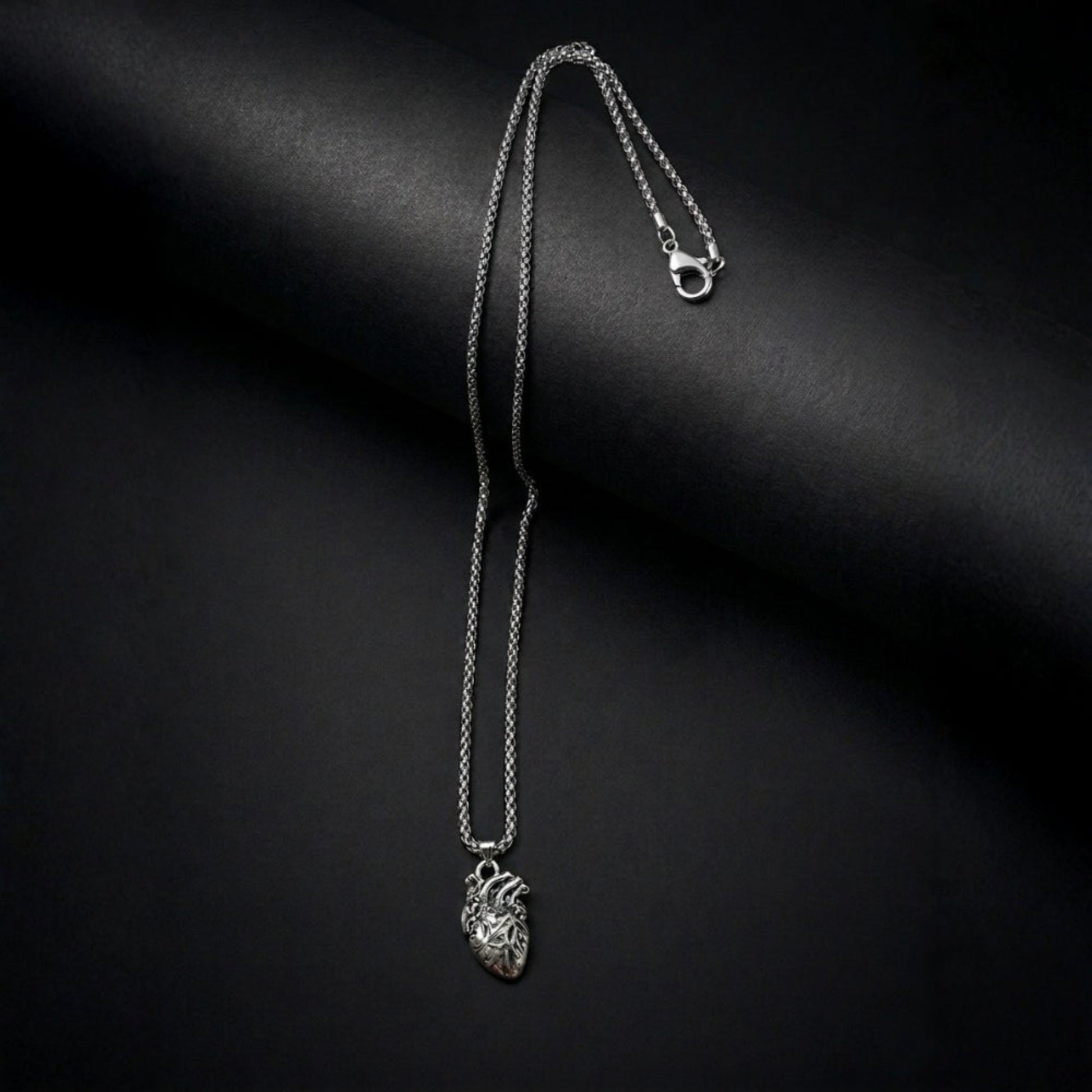 Silver necklace with a heart pendant on a black background