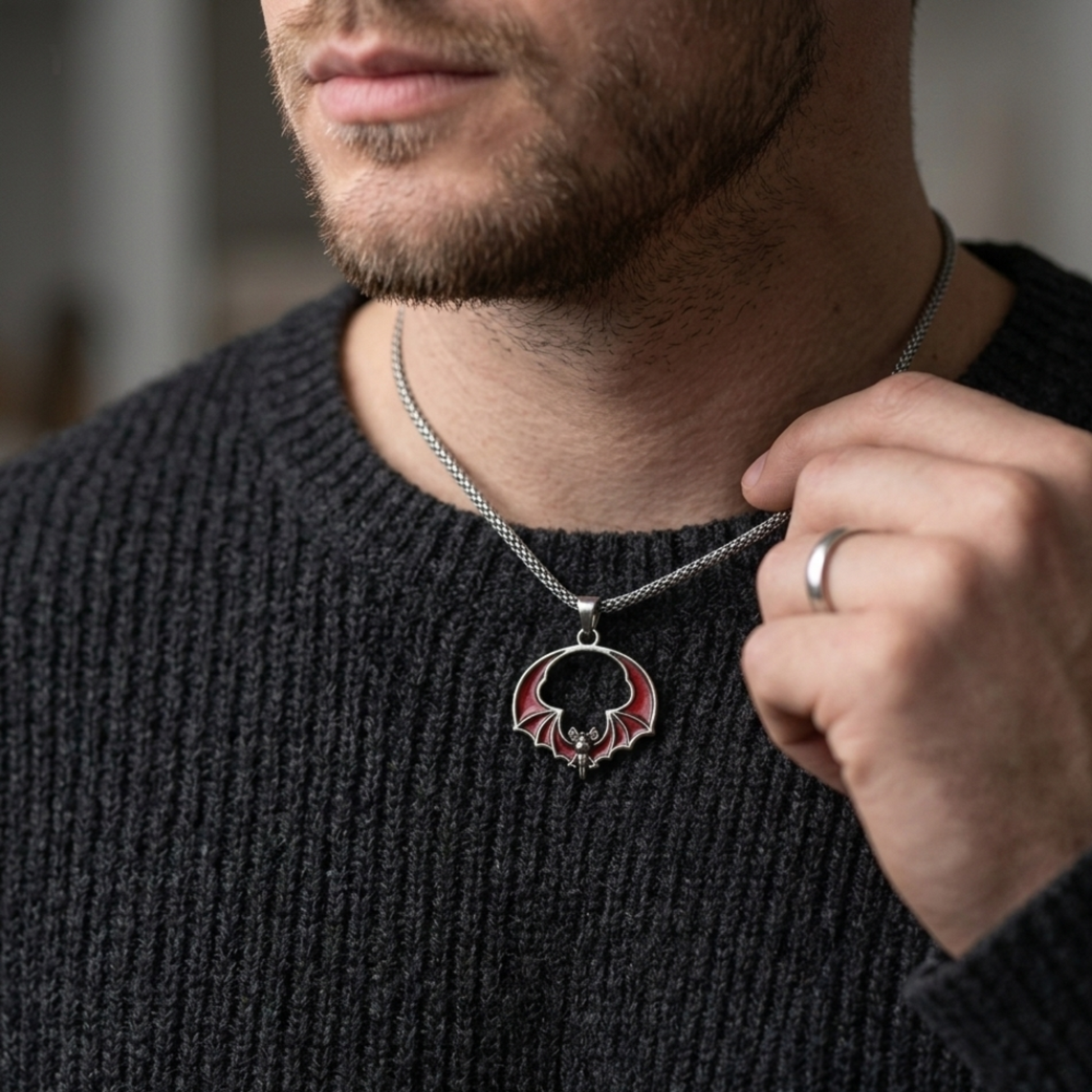 Man wearing a dark sweater with a necklace featuring a circular pendant.