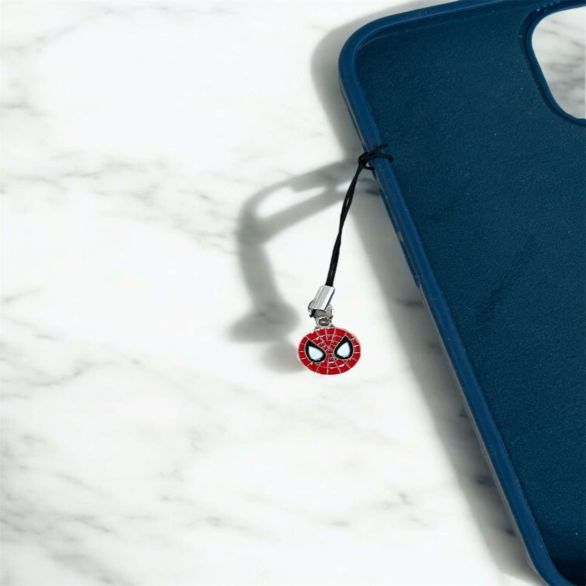 Phone charm with Spider-Man design on a blue phone case against a white marble background - Thecharmingcharms09